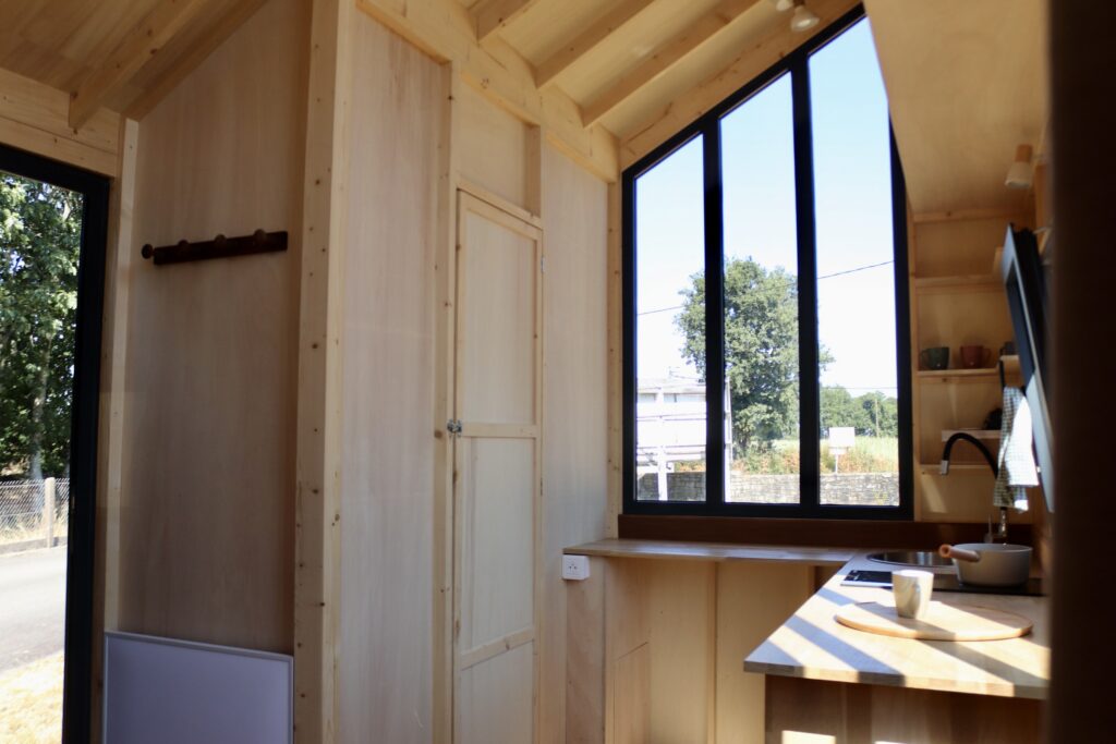 Intérieur lumineux en bois d’un studio mobile Tymup avec cuisine et grande fenêtre