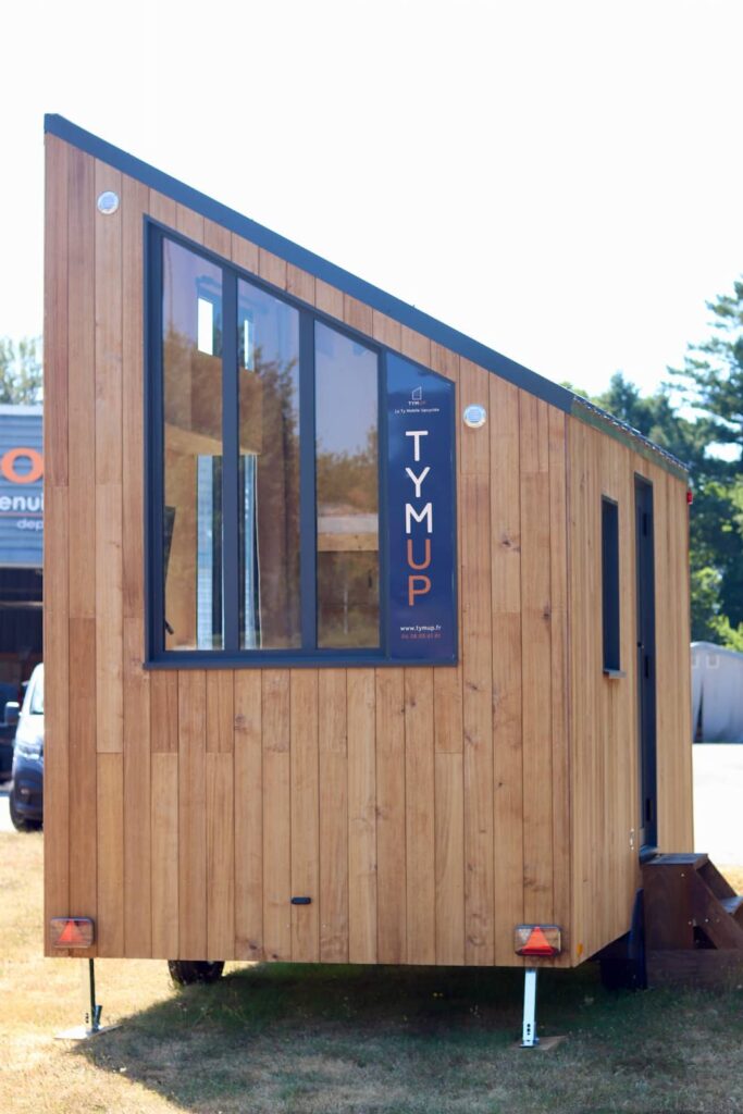 Façade du studio mobile en bois avec grande baie vitrée et enseigne TYMUP