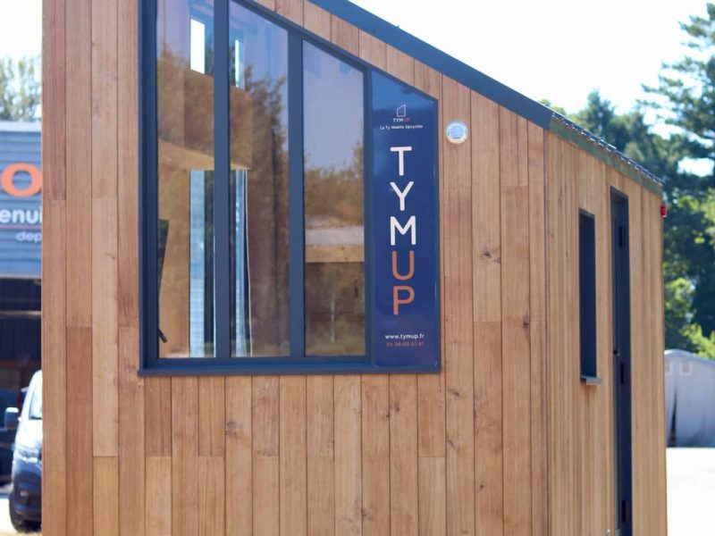 Façade du studio mobile en bois avec grande baie vitrée et enseigne TYMUP
