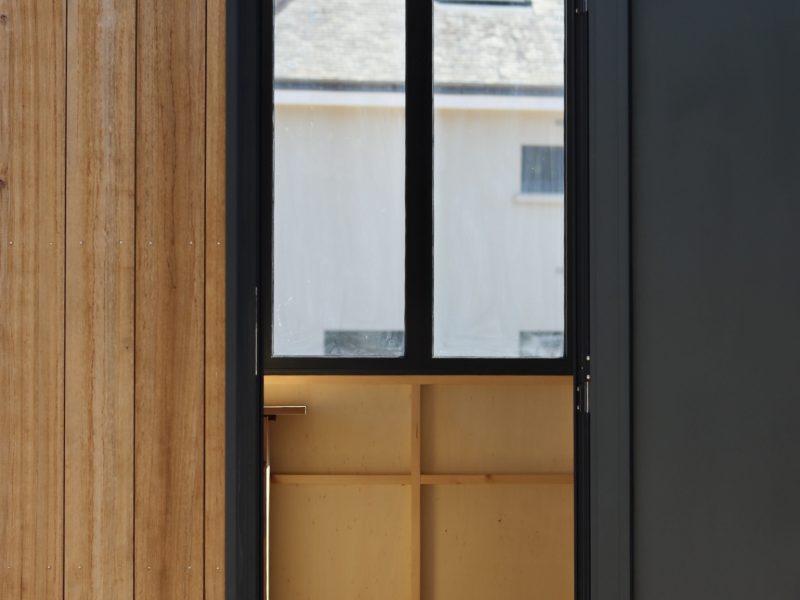 Entrée du studio TYMUP avec porte ouverte et rangements en bois