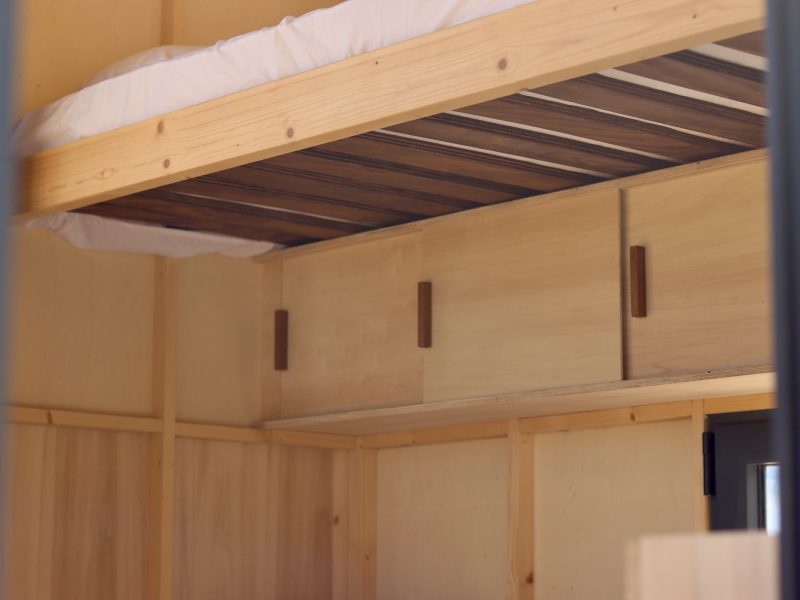 Détail du sommier relevé et des rangements en bois du studio TYMUP
