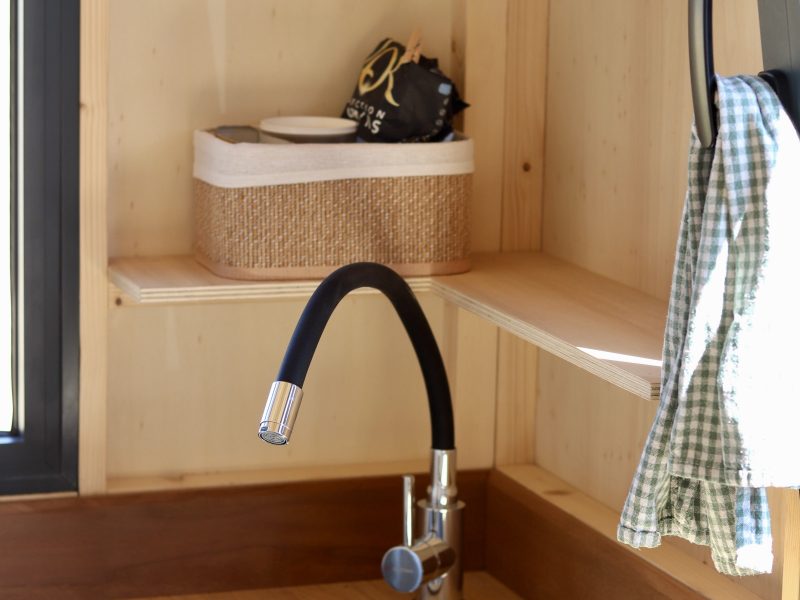 Évier rond et robinet noir dans la kitchenette en bois du studio TYMUP