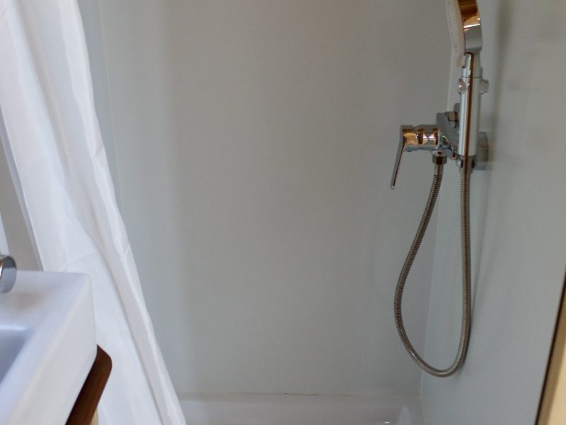 Douche avec receveur blanc et douchette dans la salle d’eau du studio TYMUP