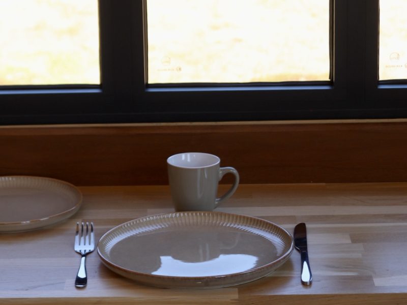 Coin repas du studio TYMUP avec table en bois dressée sous la fenêtre