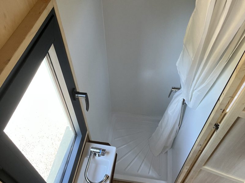 Vue en plongée sur la salle d’eau du studio TYMUP avec douche et toilettes